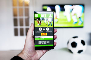 Fotballkamp på TV og betting-app på mobilen.