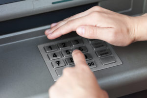 Hånd som skjuler pin-koden ved bankautomat