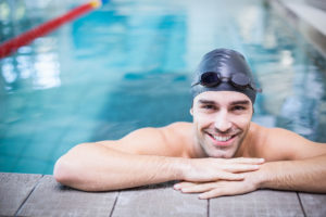 Ung smilende mann henger på kanten av et badebasseng.