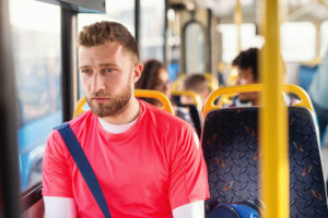 Ung mann sitter på bussen med sikkerhetsbelte på.