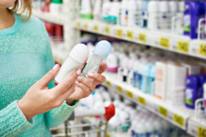 Kvinne sammenligner deodoranter i butikk.